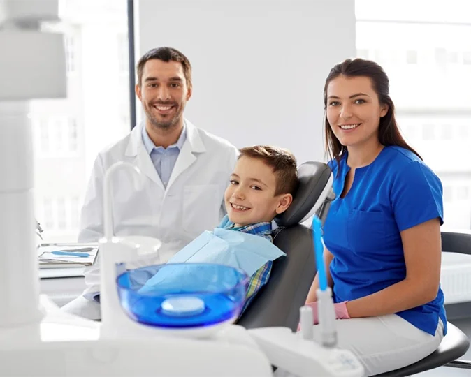 Dentist and assistant with young boy smiling in a dentist chair