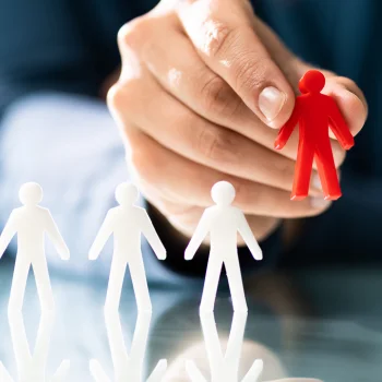 hand holding up red model man next to three white model men